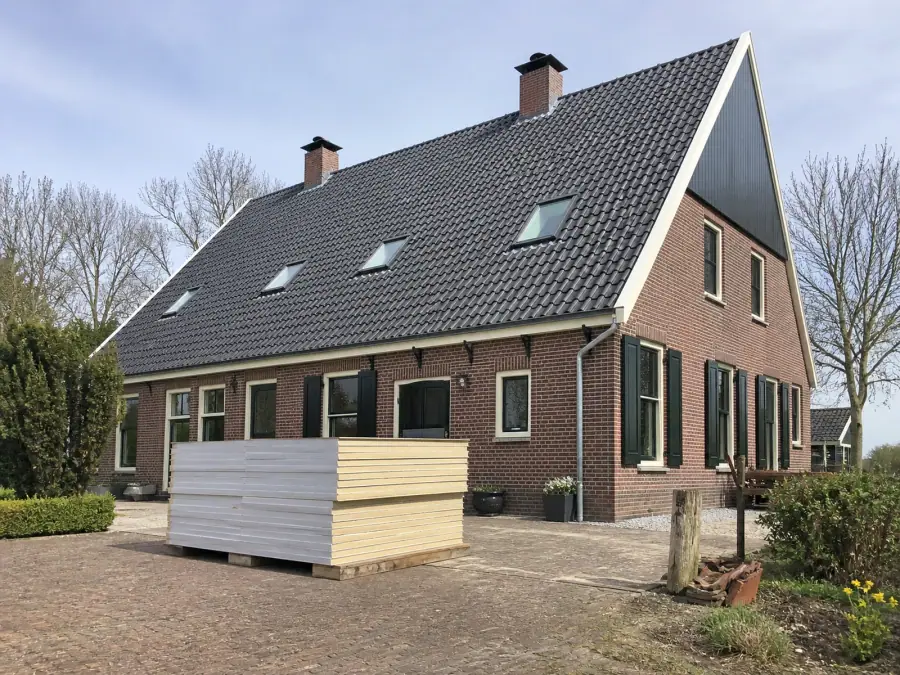 Vrijstaande woning met een groot pannendak in Overijssel, met een pallet isolatieplaten op de oprit