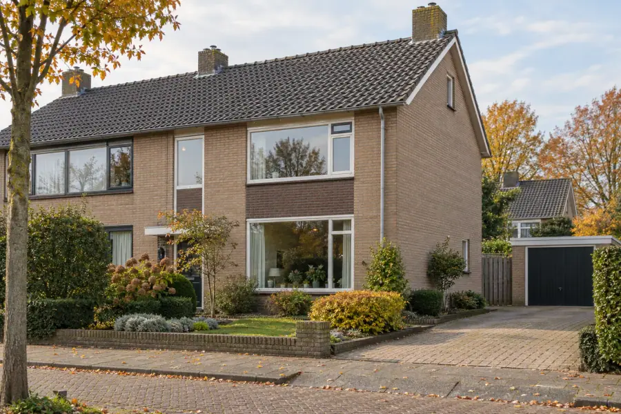 Verzorgde Nederlandse twee-onder-een-kapwoning uit de jaren zestig met zichtbare kopgevel in Hardenbergse woonomgeving